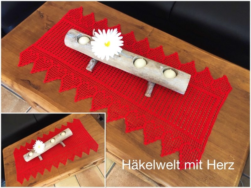 Roter gehäkelter Tischläufer mit Zackenrand, dekoriert mit einem Holzkerzenhalter und einer weißen Blüte auf einem Holztisch.