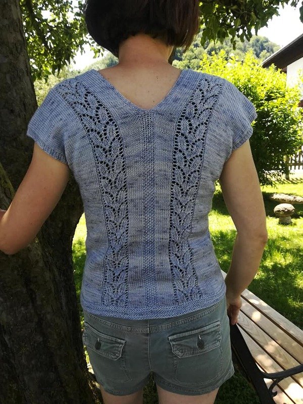Rückenansicht eines hellblauen gestrickten Shirts mit V-Ausschnitt und vertikalem Blatt-Lochmuster.