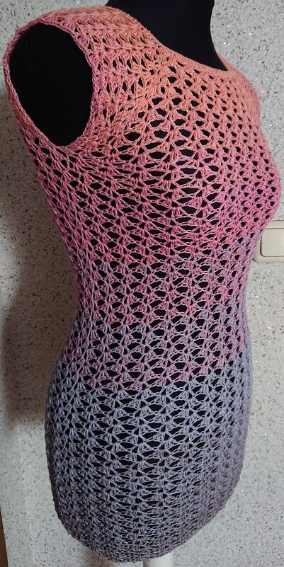 Ärmellose gehäkelte Tunika mit Farbverlauf Rosa zu Grau auf schwarzem Mannequin, offenes Spitzendesign