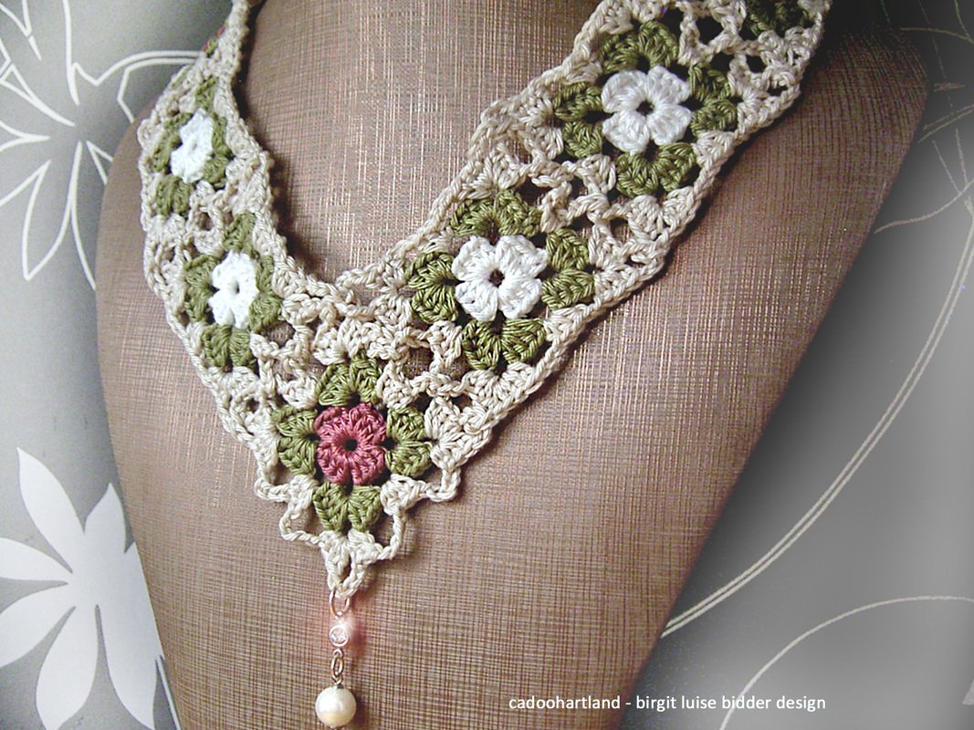 Gehäkelte Halskette aus Granny-Blüten in Beige, Oliv und Weiß mit rosafarbener Blüte und Perlenanhänger auf Schaufensterpuppe