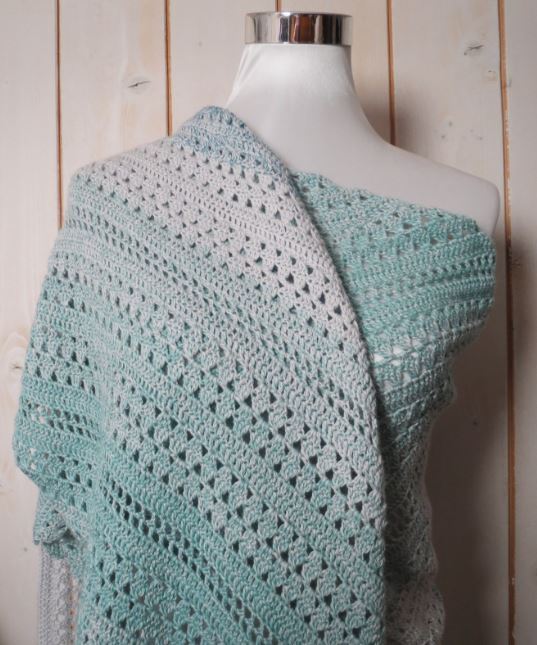 Lacy mint and gray crochet shawl draped on a mannequin