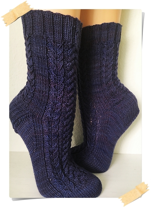 Zwei dunkelblaue, handgestrickte Socken mit Zopfmuster am Schaft und geripptem Bündchen