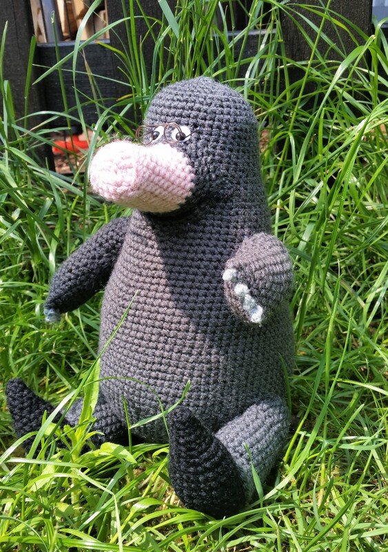Gehäkelter Maulwurf mit rosa Schnauze und Brille im Gras