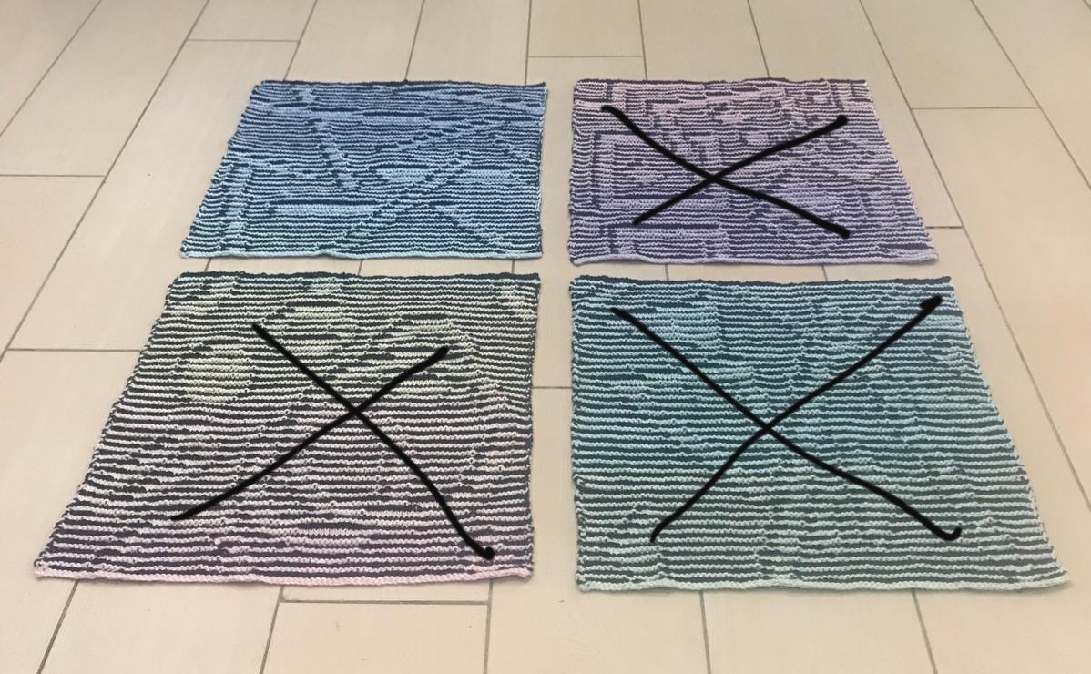 Vier gestrickte Maschenproben mit Farbverläufen in Blau, Lila, Grau und Türkis, drei davon mit schwarzem X.