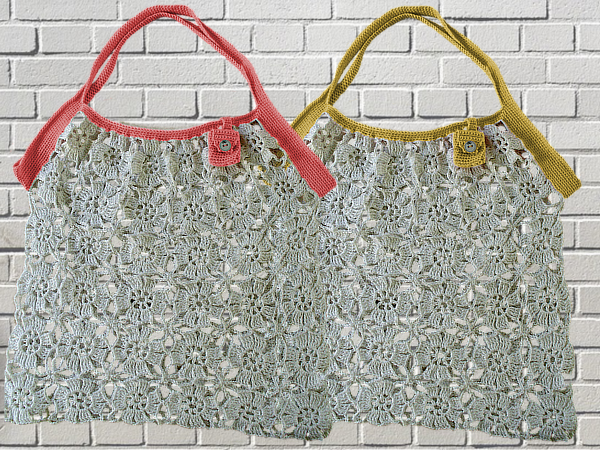 Zwei handgehäkelte Taschen aus hellgrauem Garn mit Blumen‑Lochmuster, eine mit korallenfarbenen, die andere mit senfgelben Henkeln, beide mit Knopfverschluss.