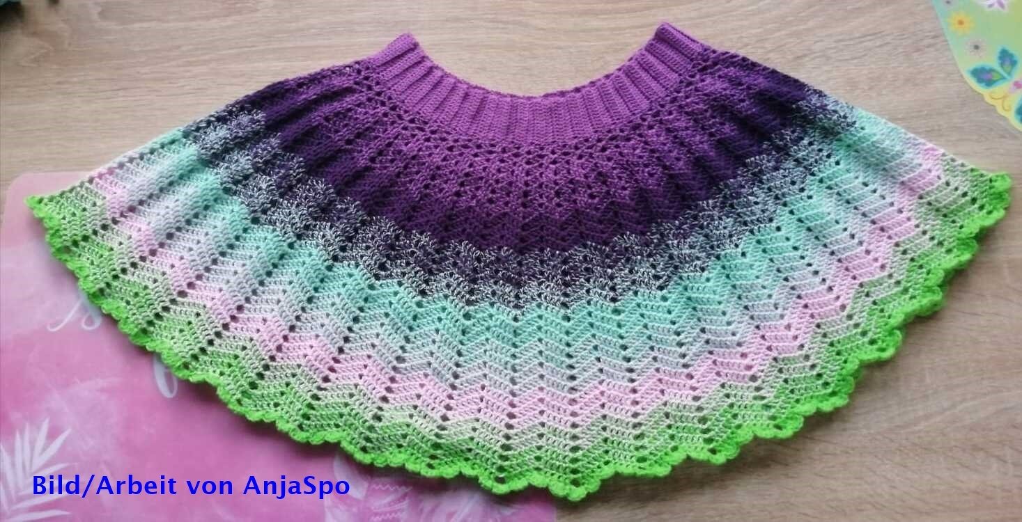 Gehäkelter Kinderrock in Violett, Mint und Grün mit Wellen- und Muschelkante, flach auf Holzuntergrund.