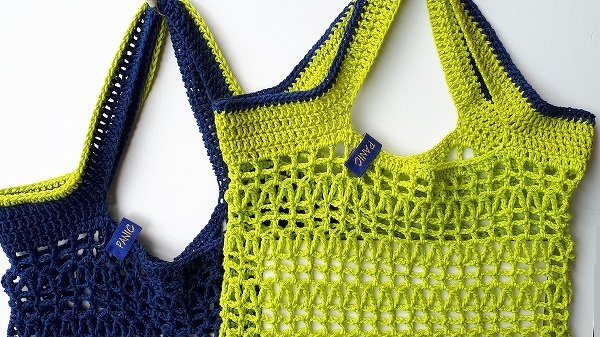 Zwei gehäkelte Netztaschen in Limettengrün und Dunkelblau mit breiten Trägern, nebeneinander liegend