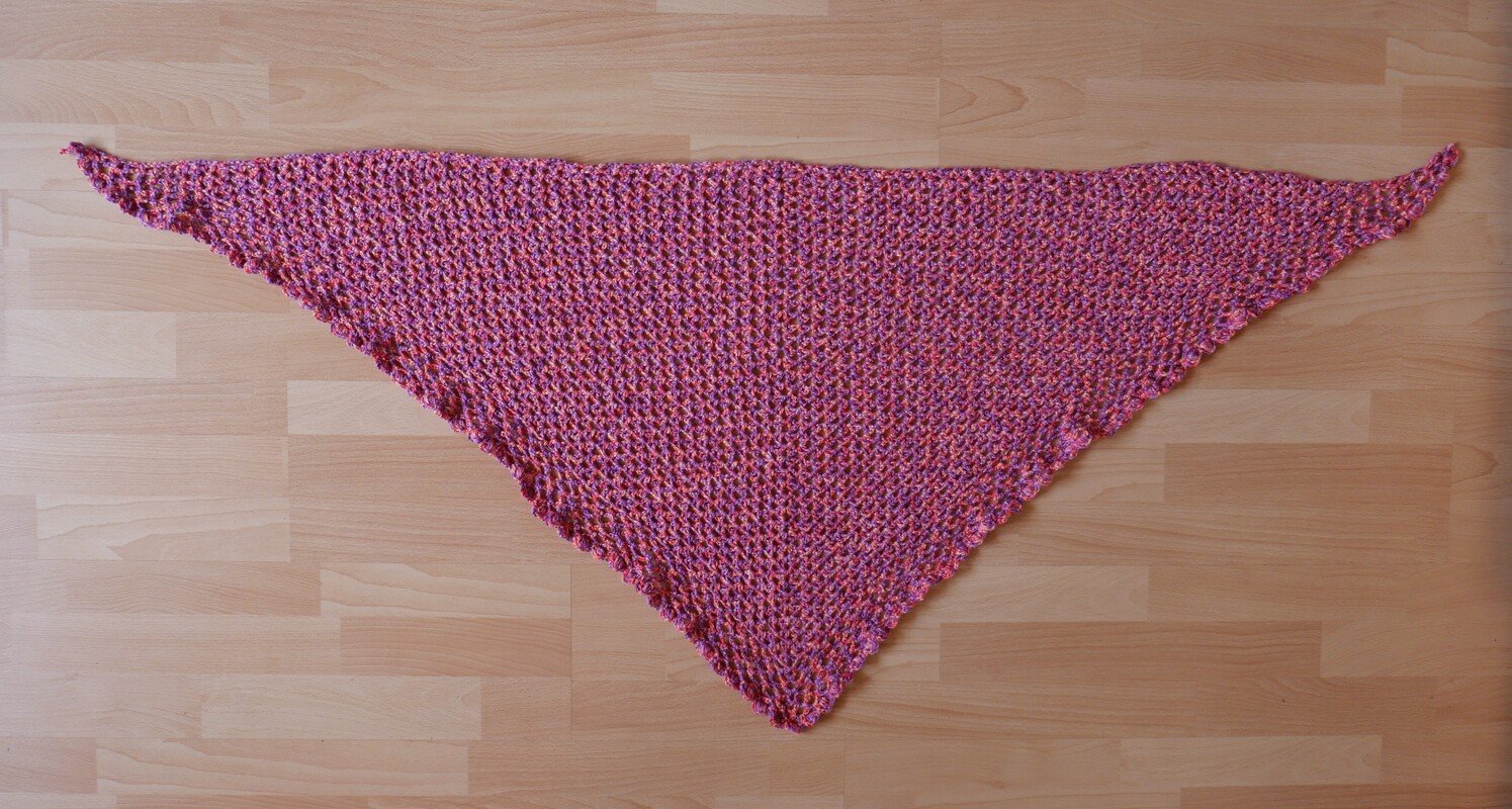 rosa gehäkeltes Dreieckstuch auf hellem Holzboden