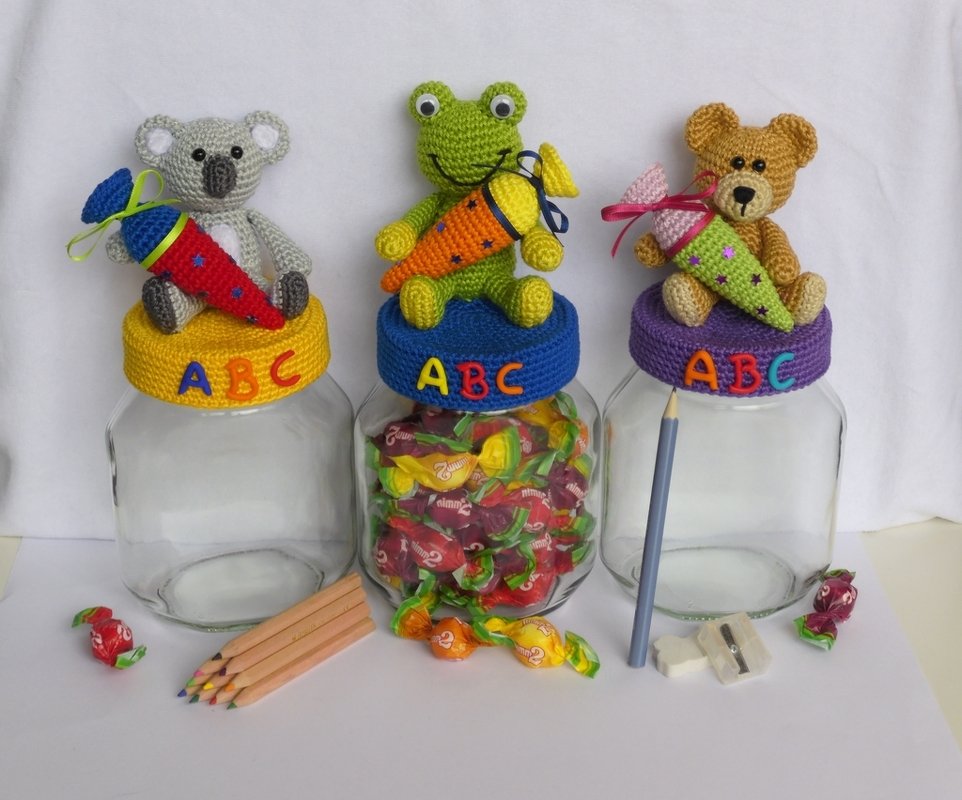Drei Glasgefäße mit gehäkelten Tierfiguren (Koala, Frosch, Bär) und kleinen Schultüten, ABC-Buchstaben auf den Deckeln