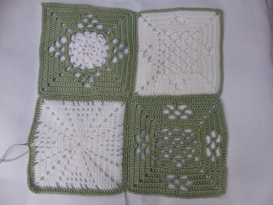 Vier verbundene Granny-Squares mit sichtbarer Naht und unterschiedlichen Häkelmustern