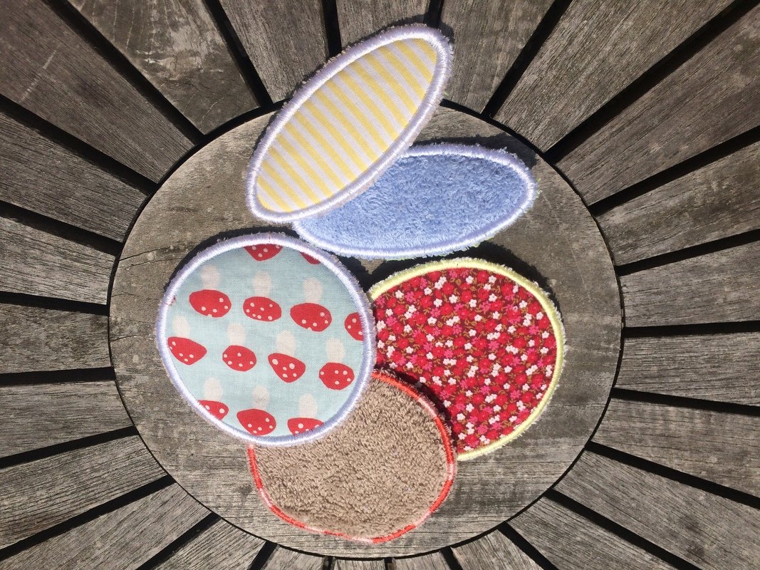 Fünf genähte ITH-Pads in runden und ovalen Formen mit Pilz-, Blumen- und Streifenmustern auf Holz.