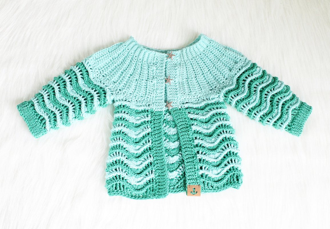 Seafoam crochet baby jacket with rippled openwork panels, ribbed yoke and star buttons