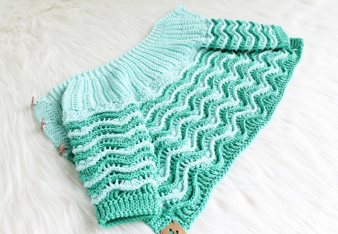 Mint green crocheted baby jacket laid flat showing ribbed yoke and ripple stitch body