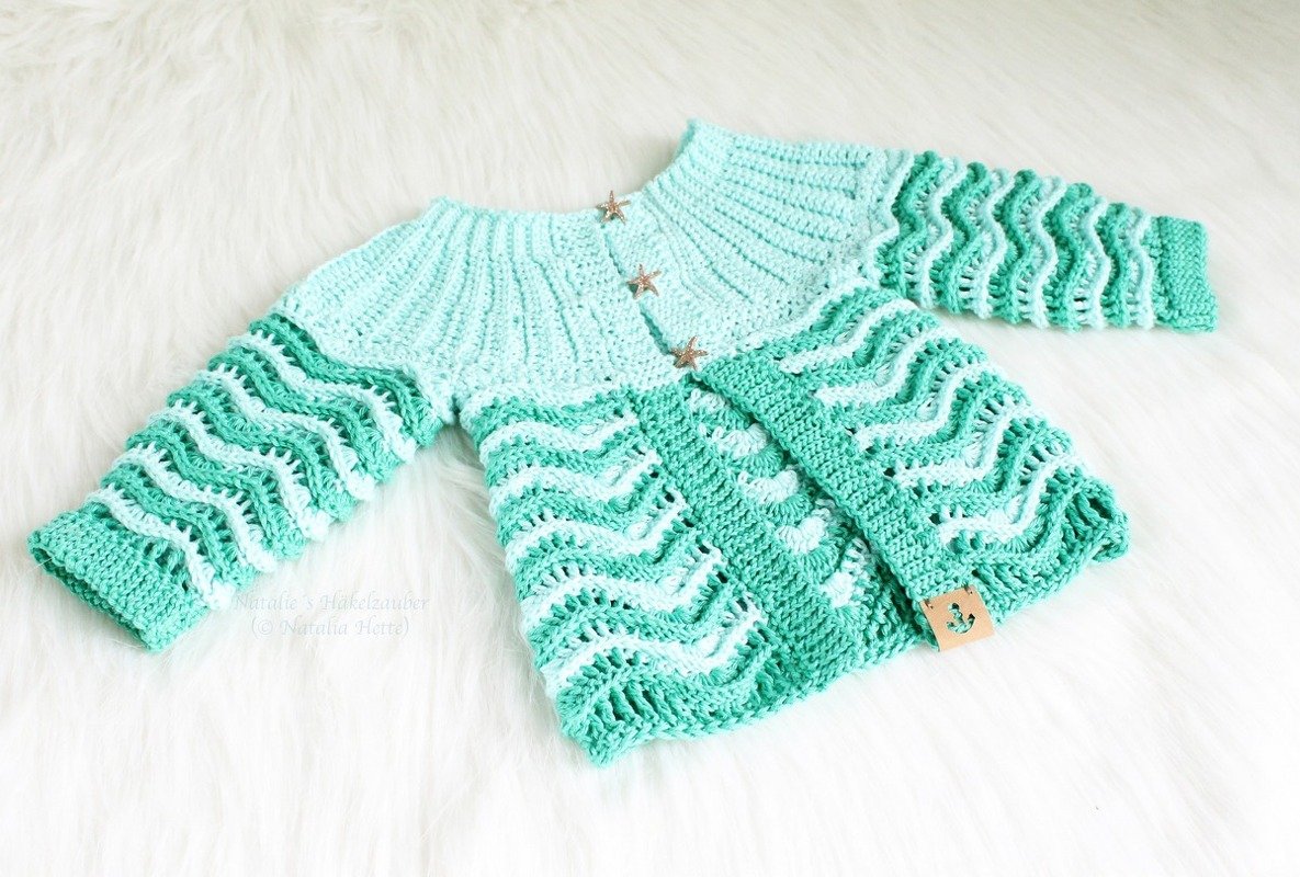 Two-tone teal crocheted baby jacket with wave stitch and three star buttons on a white background.