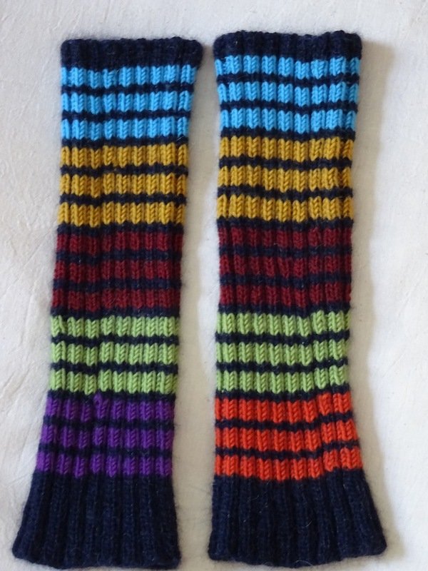 Paar gestrickter Beinstulpen mit bunten Querstreifen auf hellem Hintergrund