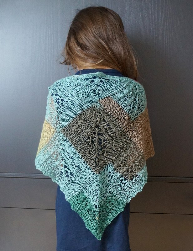 Rückansicht einer Person mit braunem Haar, die ein dreifarbiges, dreieckiges Lacetuch in Mint, Braun und Beige mit feinem Loch- und Noppenmuster trägt.