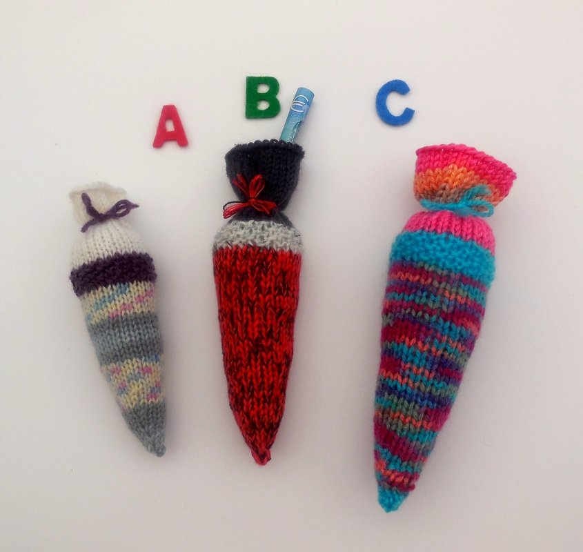 Drei bunte, gestrickte Mini-Schultüten nebeneinander