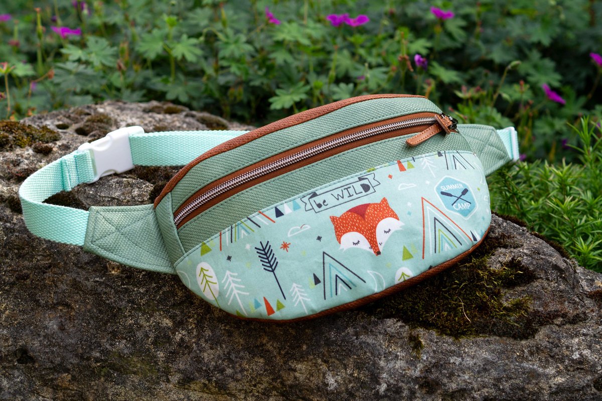 Mintgrüne Bauchtasche mit Fuchs- und Waldmotiv auf moosigem Stein