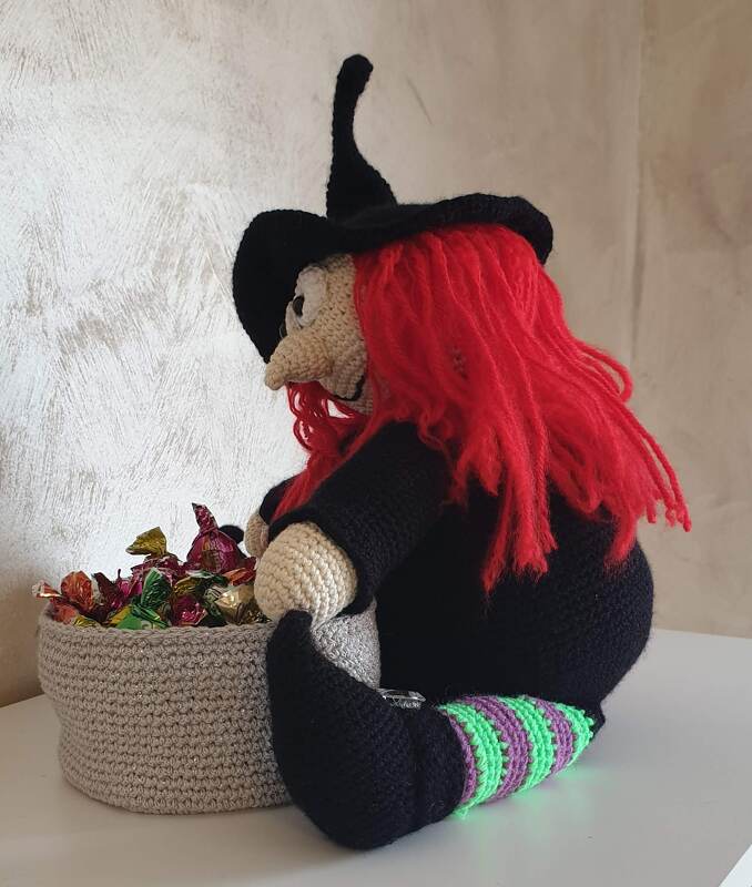 Gehäkelte Amigurumi-Hexe mit rotem Haar, schwarzem Hut und Bonbonkorb