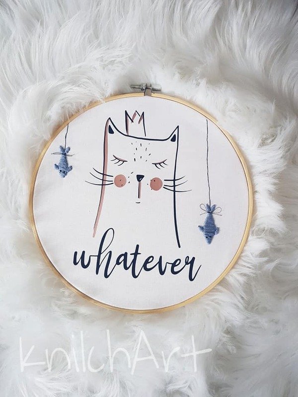 Rundes Motiv in Holzrahmen: minimalistische Katze mit Krone, zwei hängenden Fischen und dem Schriftzug „whatever“ auf weißem, flauschigem Untergrund.