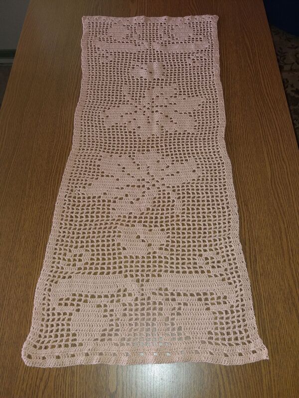 Pastellrosa Filet‑Tischläufer mit Blumen‑ und Blattmotiven auf Holztisch