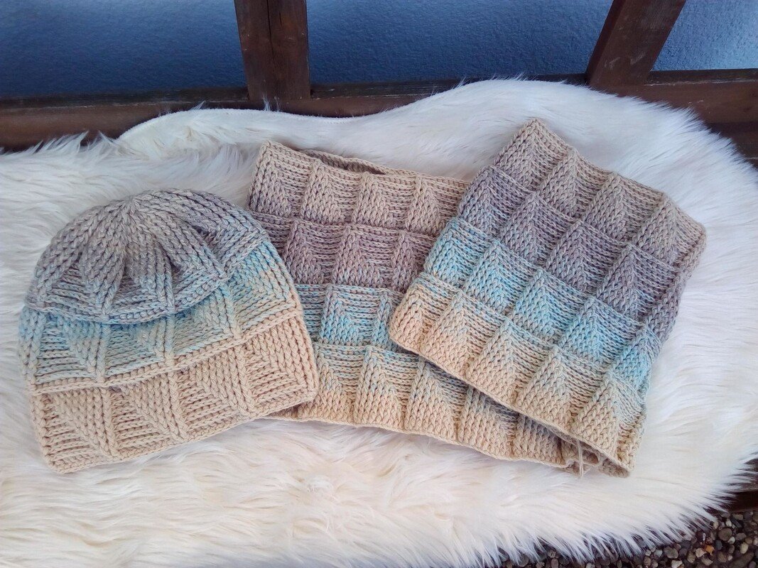 Gehäkeltes Damen-Set: Mütze und zwei Loops in Beige bis Hellblau mit kästchenartiger Reliefstruktur auf hellem Fell