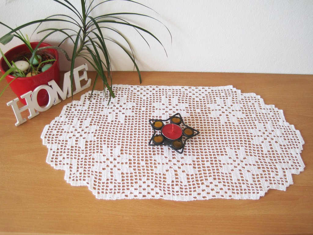 weißes gehäkeltes ovales Tischdeckchen mit floralem Muster, Kerzenhalter und Pflanze