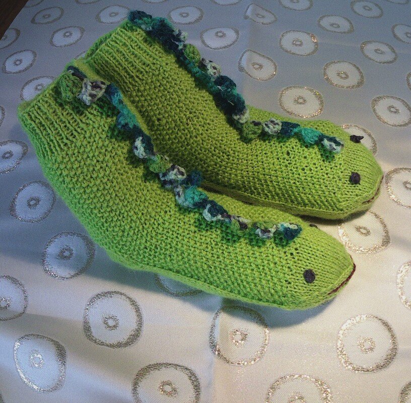Gestrickte hellgrüne Kindersocken mit Drachenzacken und aufgestickten Augen