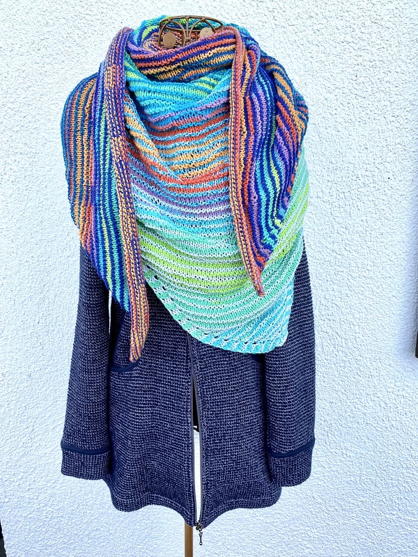 Buntes, gestricktes Dreieckstuch mit Farbverlauf über einer dunkelblauen Jacke auf Schneiderpuppe