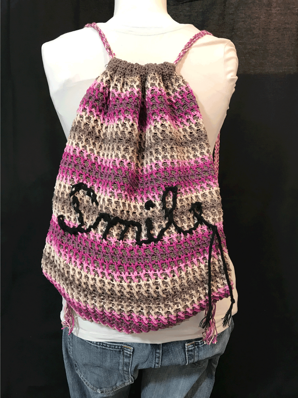 Häkelrucksack mit Streifen in Pink, Grau und Beige und schwarzem Smile-Schriftzug, Rückansicht