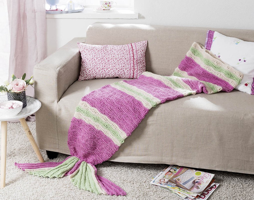 Gehäkelte Meerjungfrauen-Decke in Rosa, Hellgrün und Creme auf beigem Sofa
