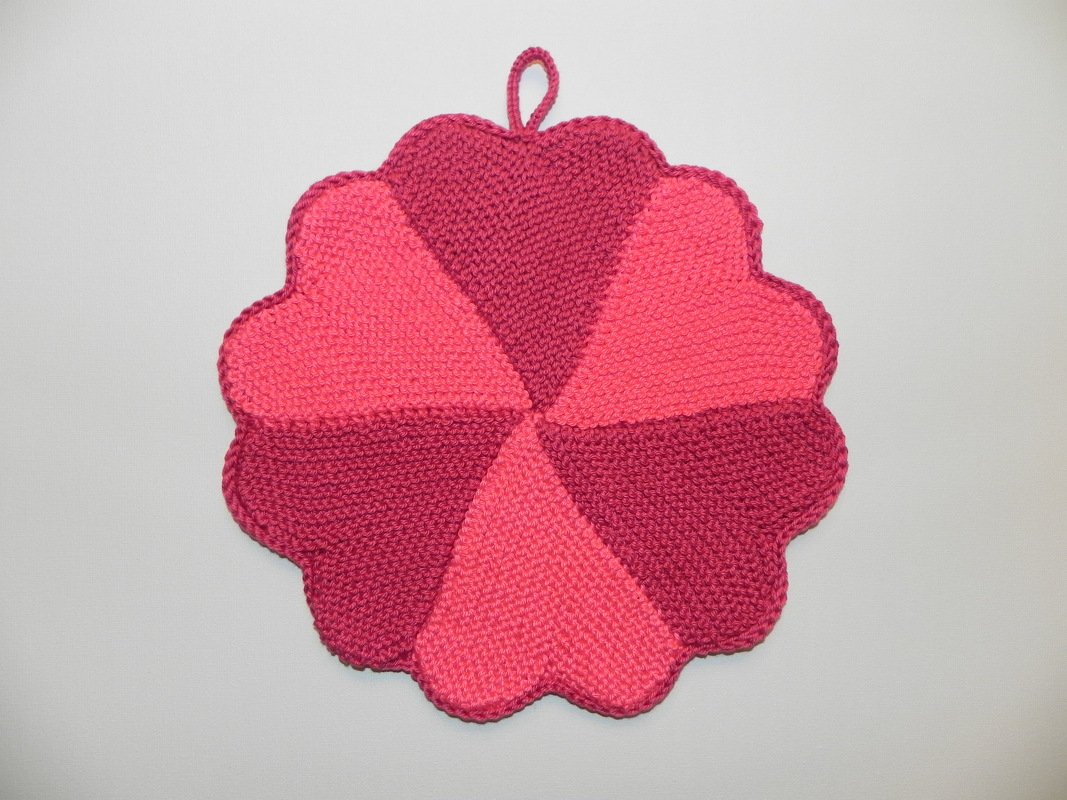 Runder gestrickter Topflappen in Blumenform mit sechs Segmenten in zwei Pinktönen und Aufhängeschlaufe