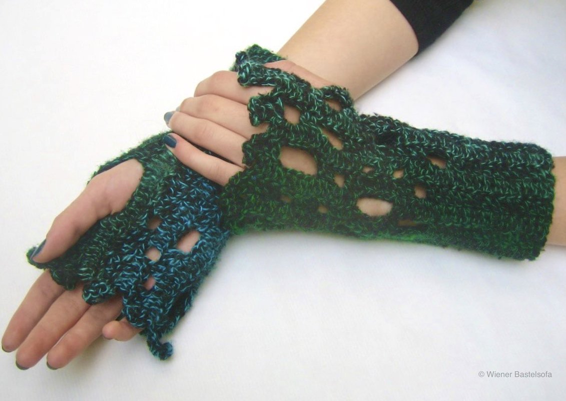 Gehäkelte fingerlose Handschuhe in Grün‑Blau mit offenem Lochmuster, getragen