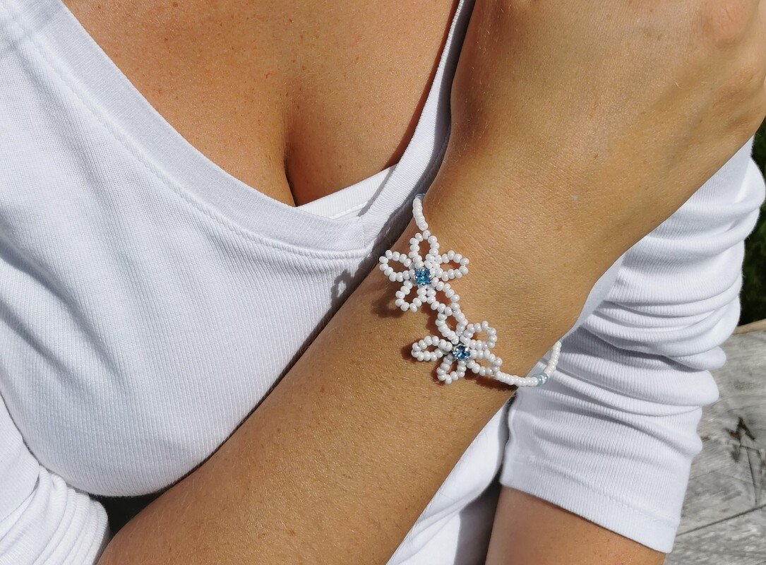 Gefädeltes Armband mit weißen Perlen und blauen Mittelperlen am Handgelenk