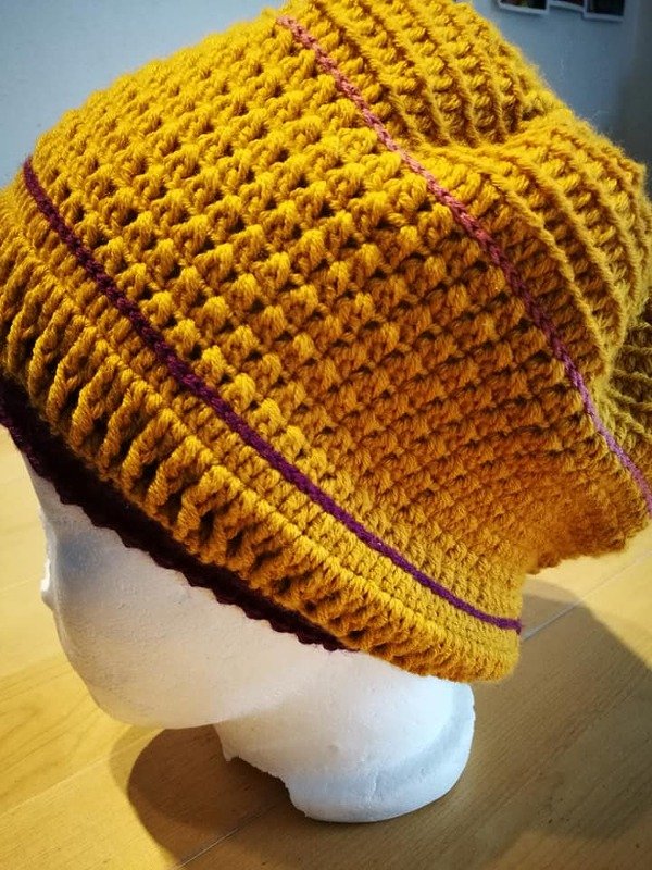 Gehäkelte Beanie in Senfgelb mit lila Streifen auf Styroporkopf
