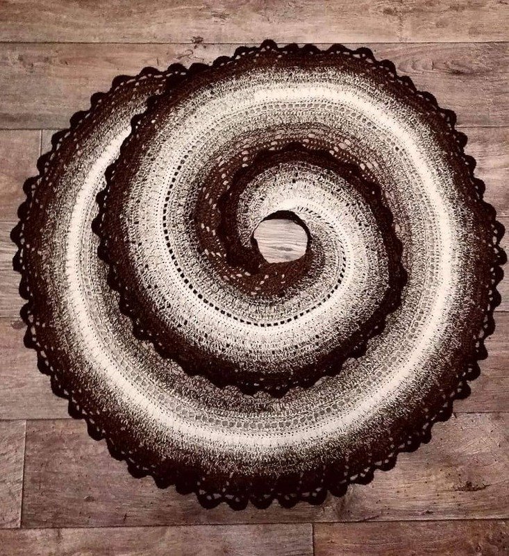 Rundes gehäkeltes Tuch in Braun und Weiß mit Spiralmuster auf Holzboden