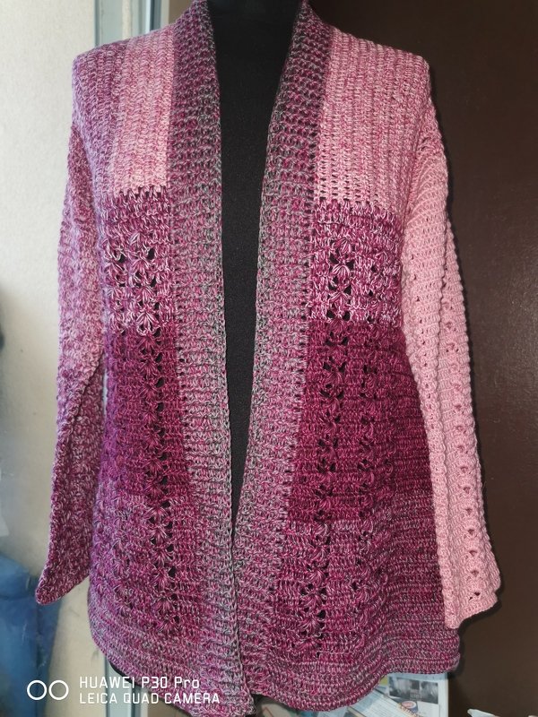 Gehäkelte Damenjacke in Rosa- und Bordeauxtönen auf schwarzer Schneiderbüste, offener Schnitt mit Schalkragen