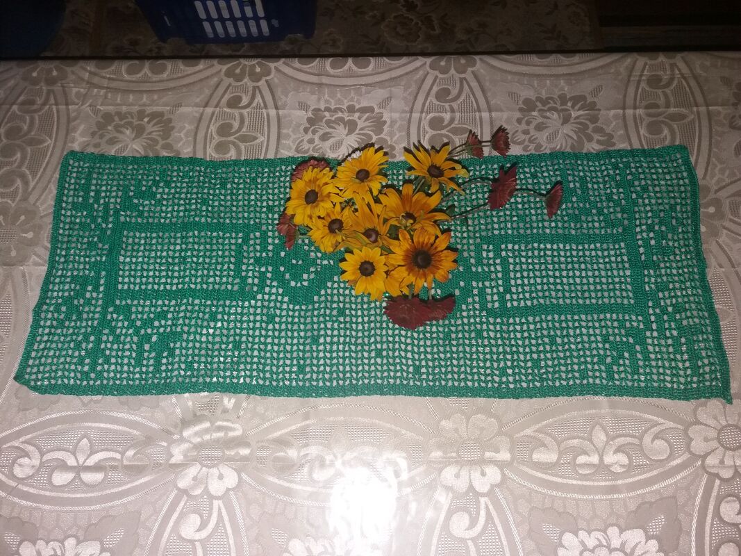 Grüner gehäkelter Tischläufer im Filetmuster mit gelben Blumen darauf