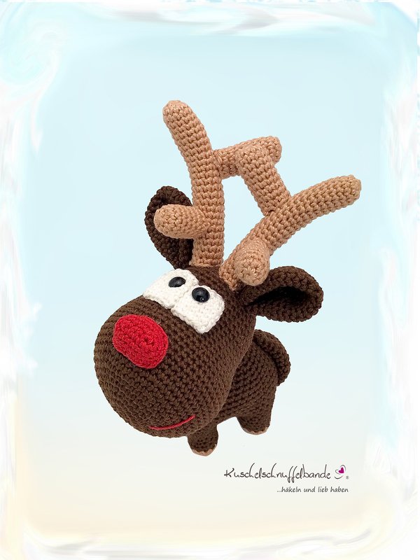 Gehäkeltes braunes Rentier-Amigurumi mit roter Nase, weißen Augen und hellbraunem Geweih vor hellblauem Hintergrund.