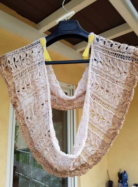 Beiger Loop‑Schal mit filigranem Spitzenmuster an einem Kleiderbügel