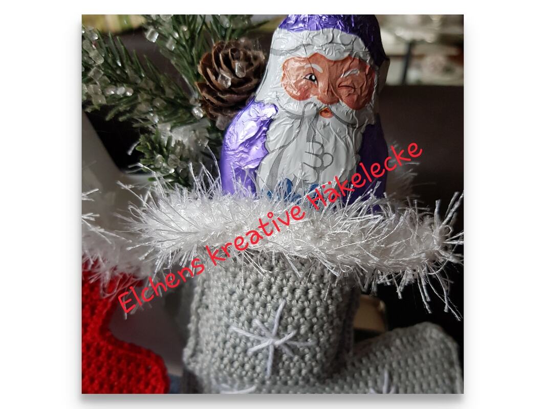 Gehäkelter grauer Weihnachtsstiefel mit weißem flauschigen Rand, bereit zum Befüllen.