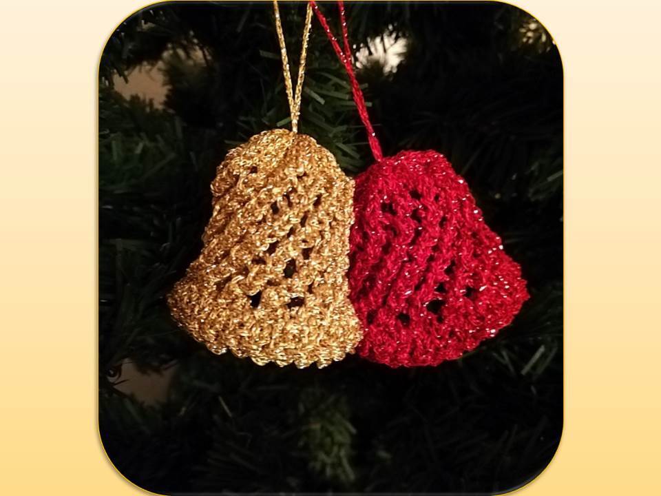 Zwei gehäkelte Weihnachtsglocken in Gold und Rot an einem Tannenzweig.