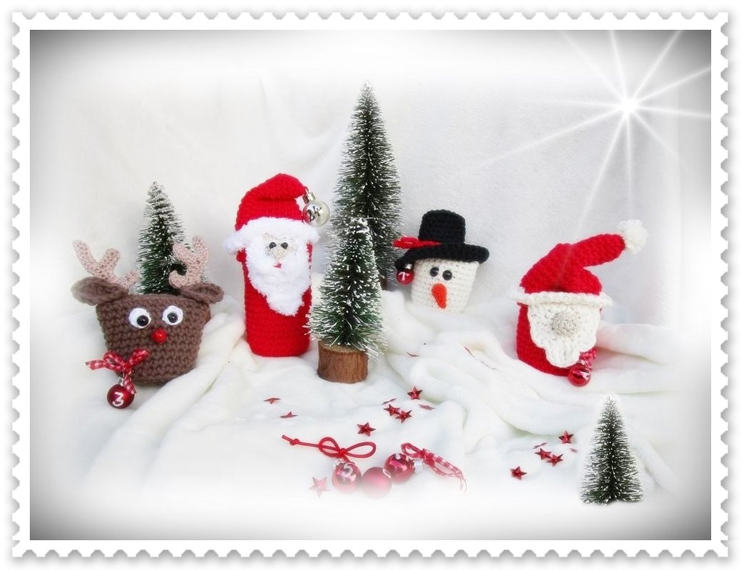 Mini-Häkelfiguren: Rentier, zwei Weihnachtsmänner, Schneemann, Mini-Tannenbäume und rote Kugeln auf weißer Unterlage