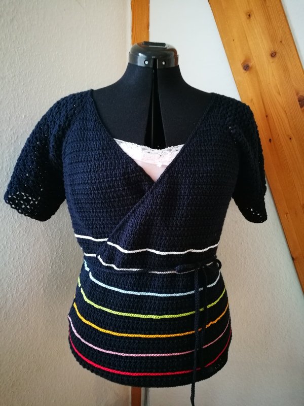 Dunkelblaue gehäkelte Wickelbluse mit V-Ausschnitt, kurzen Ärmeln und bunten Querstreifen am Saum auf einer Schneiderpuppe