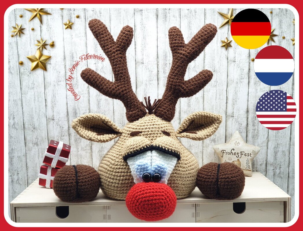 crocheted reindeer head with red nose, brown antlers, and button eyes on a wooden backdrop
