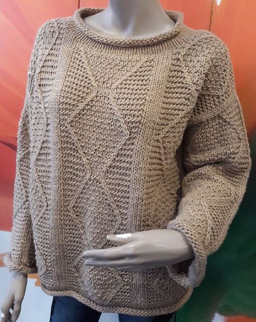 Grob gestrickter beiger Pullover mit Rauten- und Zopfmuster auf Schaufensterpuppe