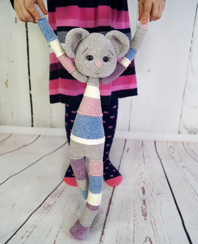 Gehäkelte Amigurumi‑Maus mit Pastellstreifen, von einem Kind an den Händen gehalten