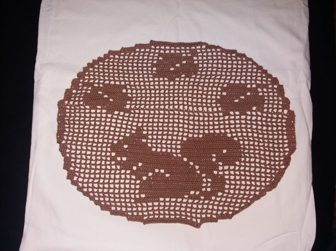 Rundes braunes Häkeldeckchen mit durchbrochenem, dekorativem Muster auf weißem Stoff