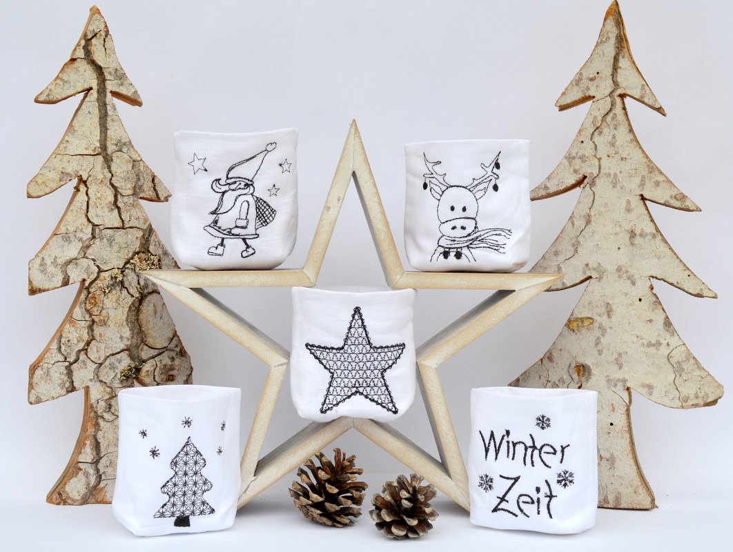 Fünf weiße bestickte ITH-Hüllen für LED-Tischlichter mit Wichtel, Rentier, Stern, Weihnachtsbaum und dem Schriftzug „Winter Zeit“ auf einem sternförmigen Holzständer, umgeben von Holzdekorationen und Tannenzapfen.