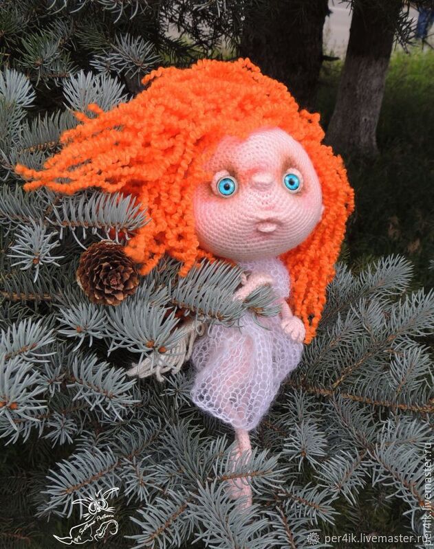 Handgehäkelte Amigurumi-Puppe mit orangefarbenen Locken und blauen Augen auf einem Fichtenzweig neben einem Kiefernzapfen